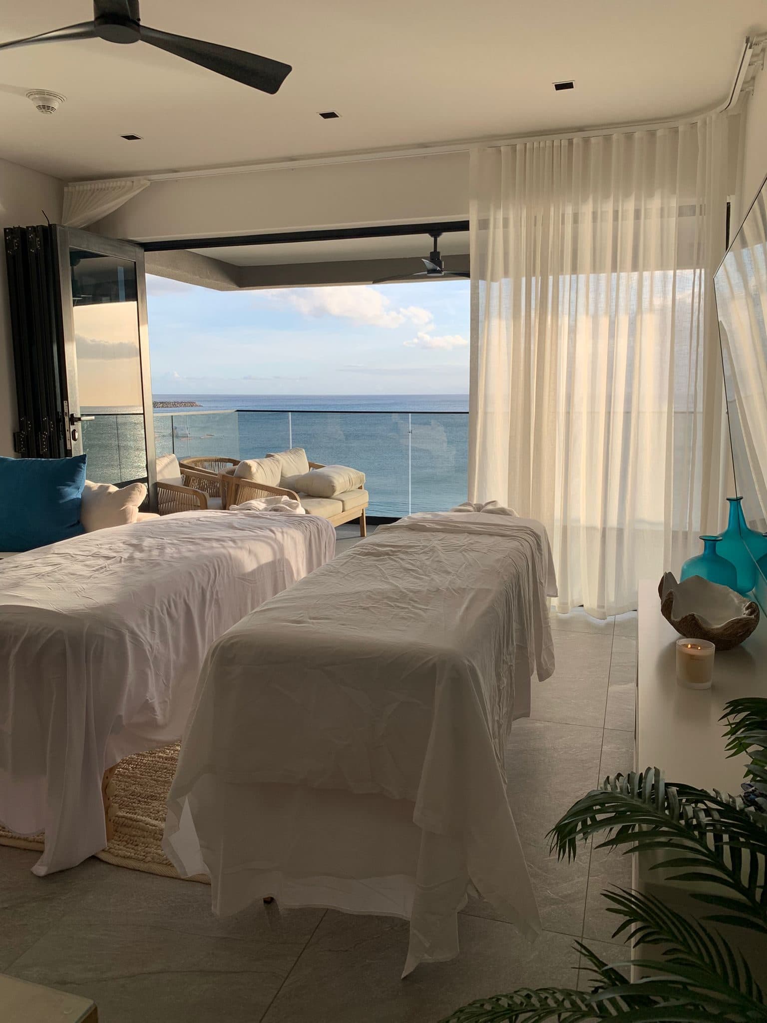 Two massage tables side by side in an oceanfront room, set up for a couples massage in Barbados