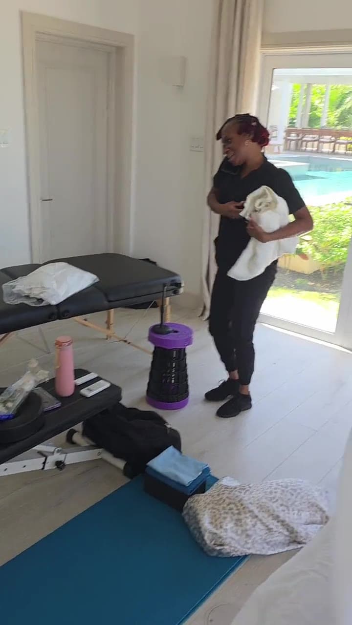 Therapist preparing a massage table on a sunlit deck with the sea beyond, an in-room spa treatment in Barbados